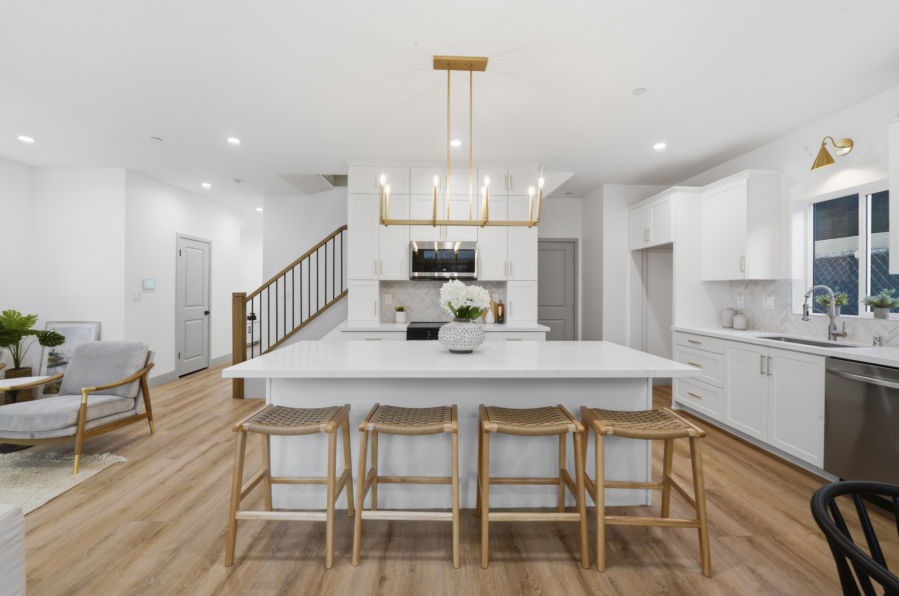 Plan B kitchen island with linear chandelier and woven stools