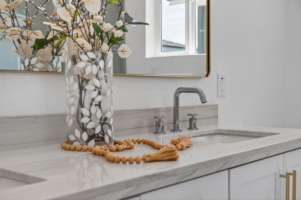 Vanity detail with brushed gold faucet and floral arrangement